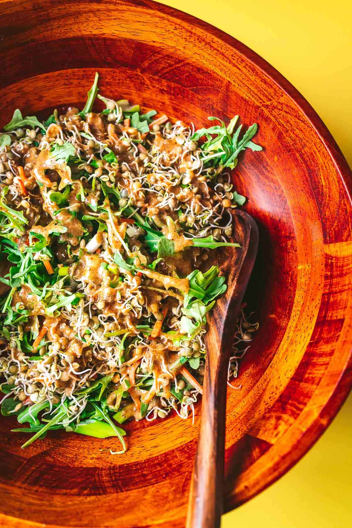 A large wooden salad bowl filled with a vibrant green salad.