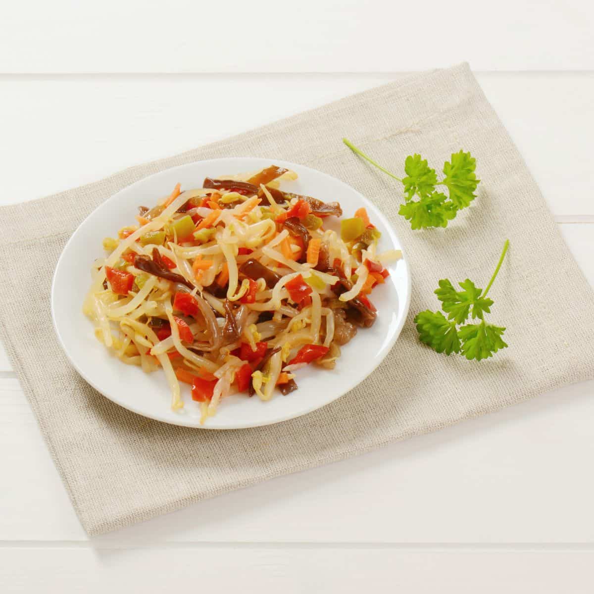 A plate of pasta with vegetables and **parsley**.