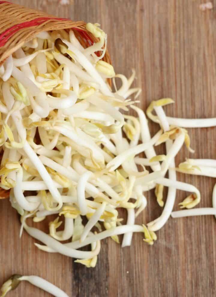 Sprouts nestled in a basket on a rustic wooden table.