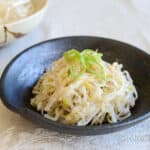 A bowl of noodles and a bowl of green onions.