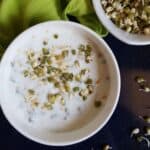 A bowl of yogurt with sprouts and seeds.