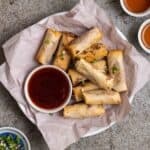 Chinese spring rolls on a plate with dipping sauce.